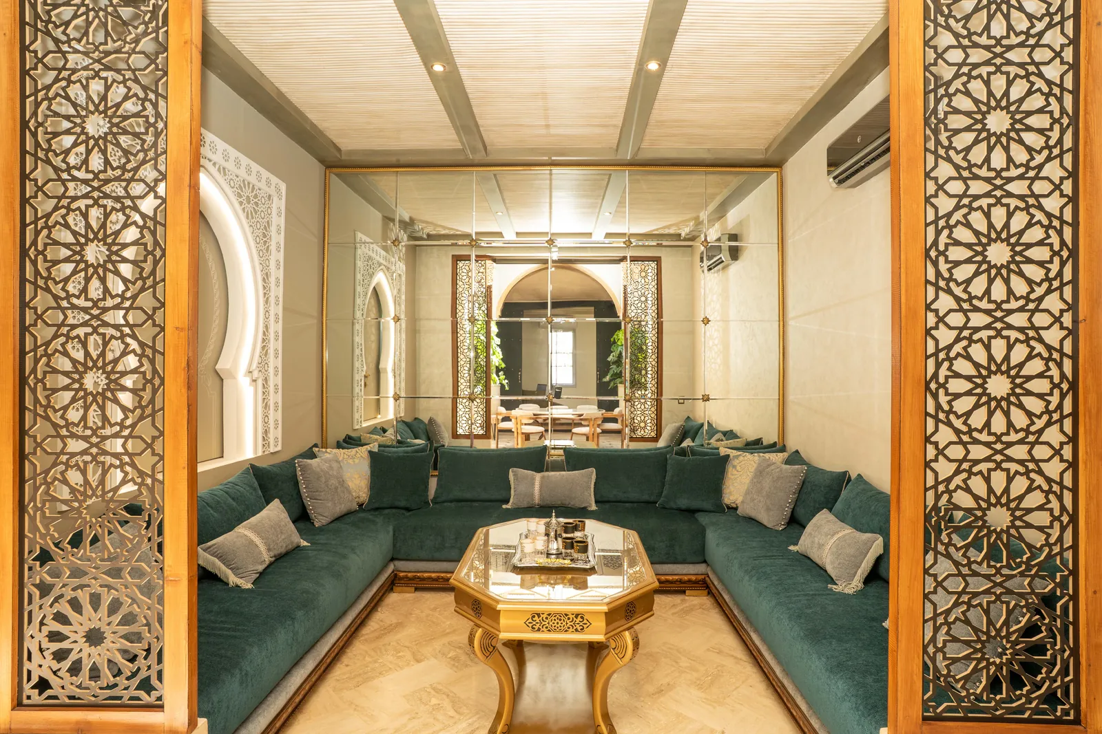 Moroccan living room with green seating and carved door surrounds